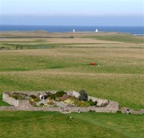 Castle Garden at Lindisfarne with sailboats behind.